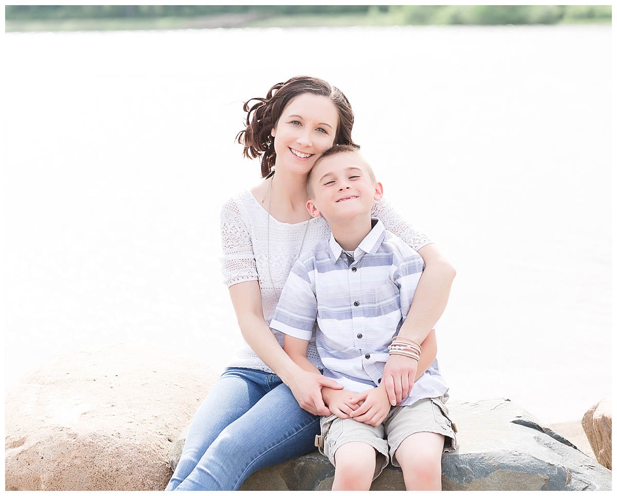 mother and son sitting on large rock along beach