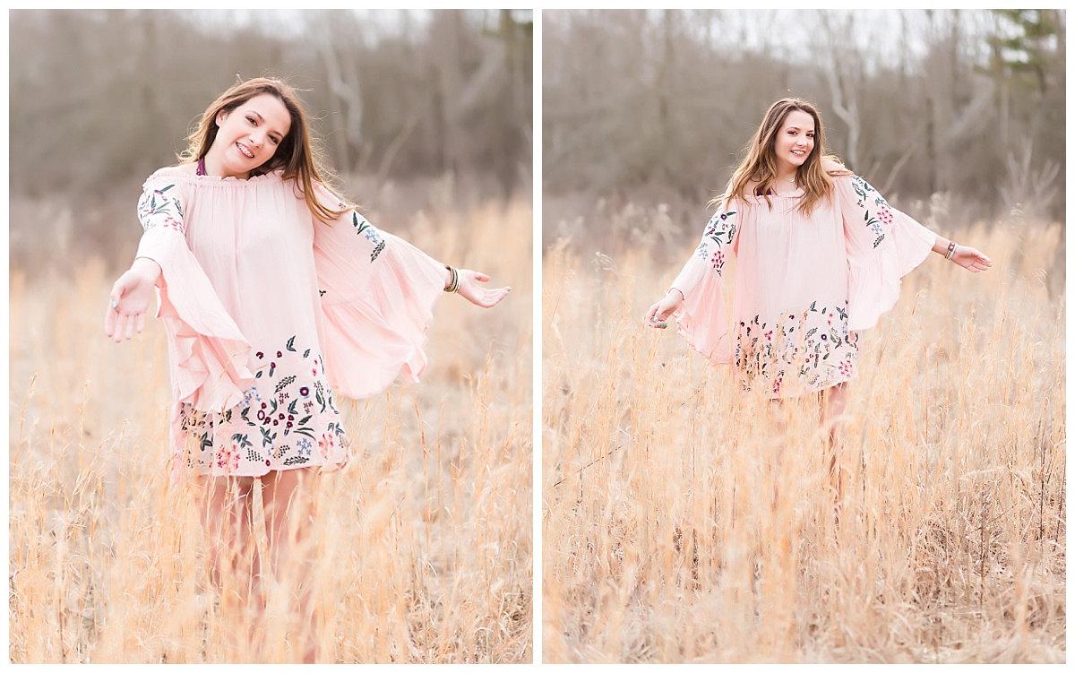 Senior girl in pink dress walking in field of tall grass