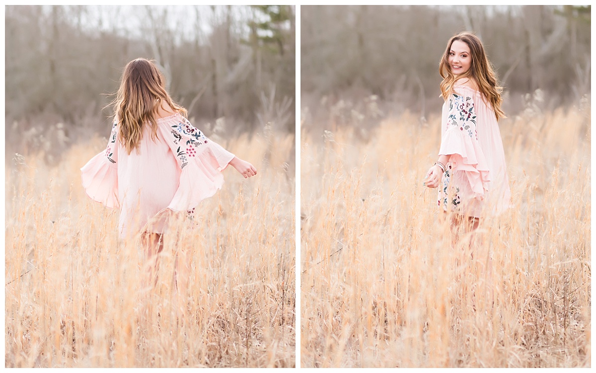 Senior girl in pink dress twirling in field of tall grass