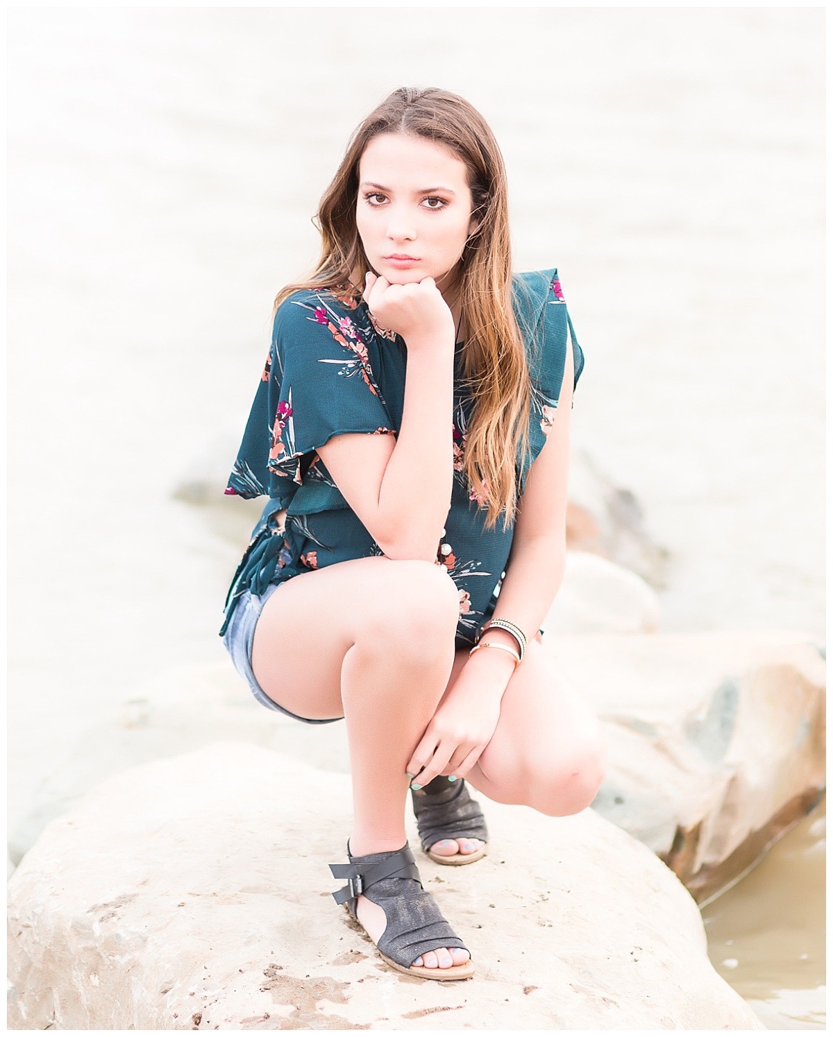 senior girl kneeling on rocks at beach