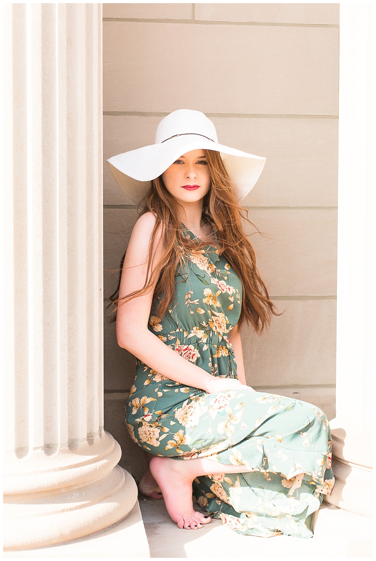 senior girl between columns wearing hat